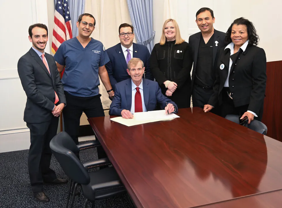On the dotted line: Dr. Mouhab Rizkallah (second from left) with other dentists and Massachusetts Secretary of the Commonwealth William Francis Galvin (seated) in December 2022, celebrating the passage of Question 2 in a statewide referendum.