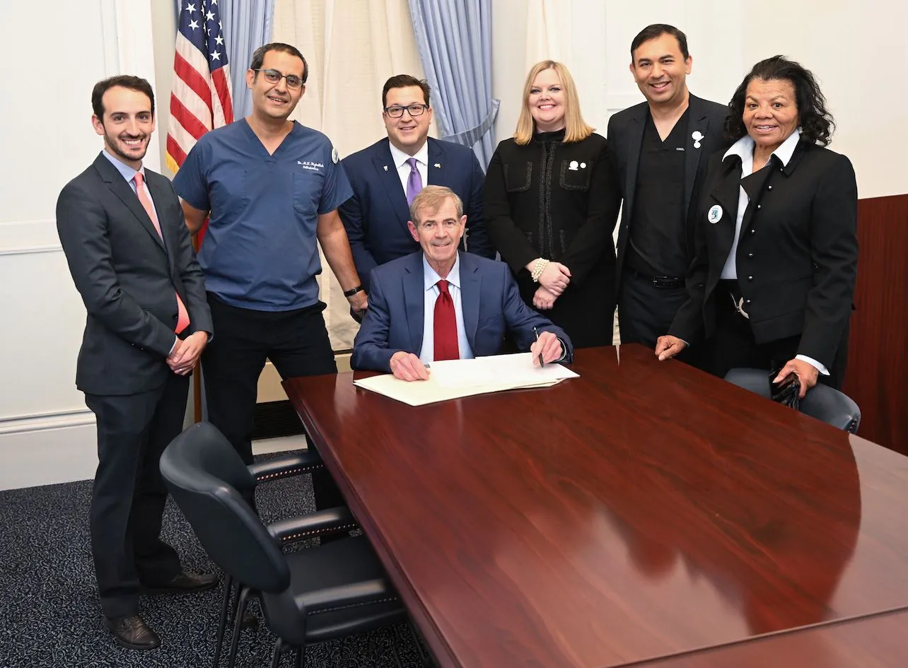 On the dotted line: Dr. Mouhab Rizkallah (second from left) with other dentists and Massachusetts Secretary of the Commonwealth William Francis Galvin (seated) in December 2022, cele­brating the passage of Question 2 in a statewide referendum.