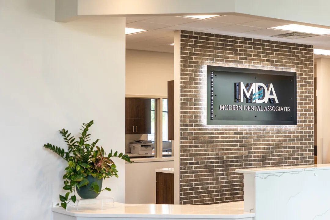 Warm welcome: “Dr. Parry wanted a bright space with whites and gray/beige tones with exposed brick and open ceiling, mid to dark wood tones, concrete, glass door and Midcentury Modern furniture,” says designer Amy Hnat. 